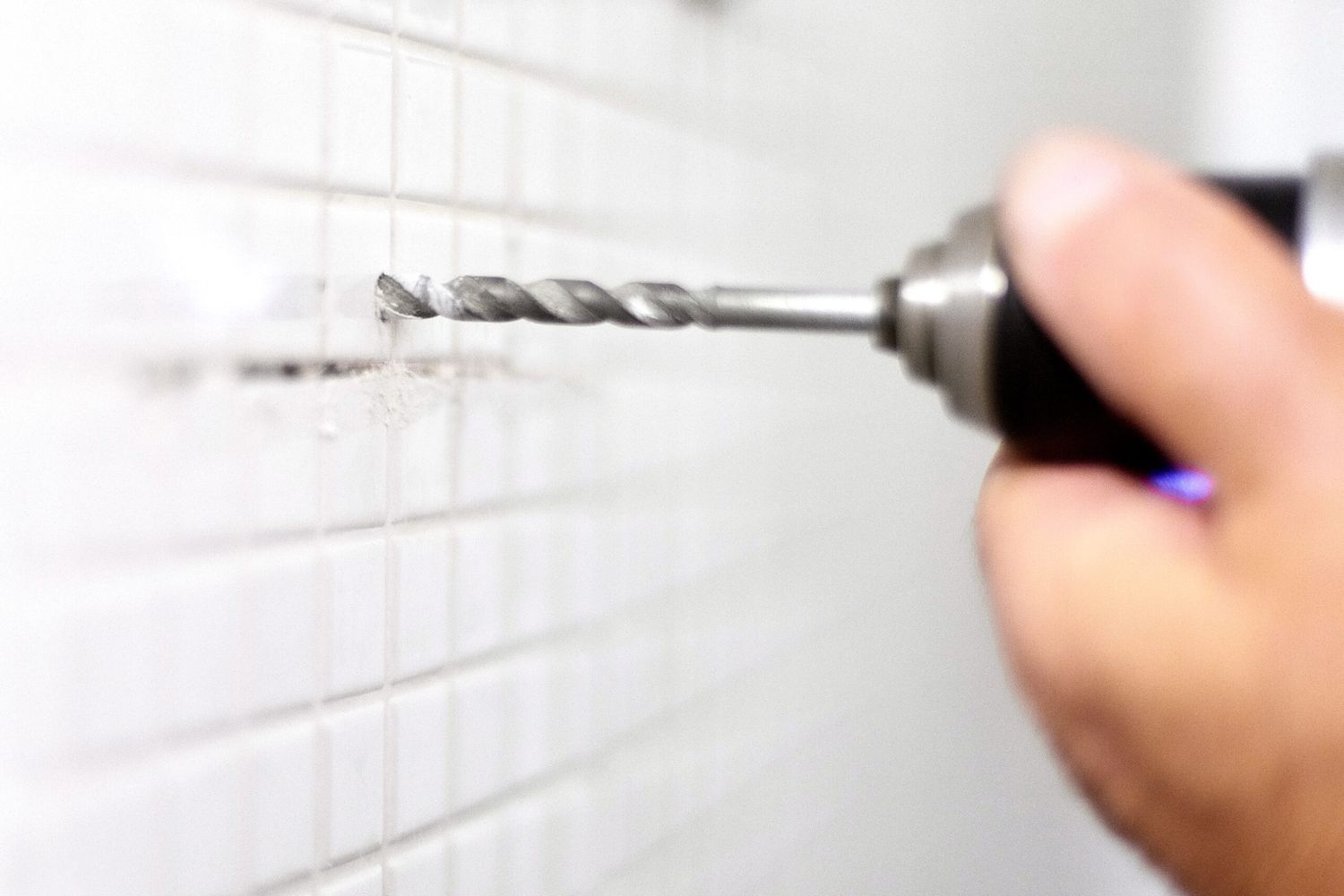 A person drilling a hole into ceramic tile.