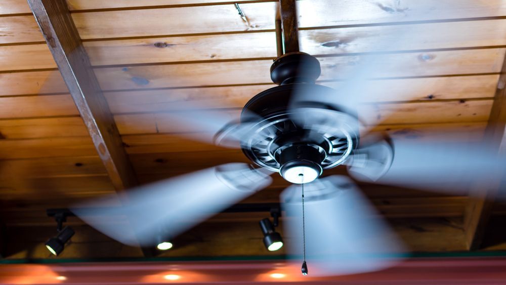 A ceiling fan shows motion blur as its blades spin around.