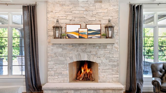 A stone fireplace with a mantel above it holding framed photos.