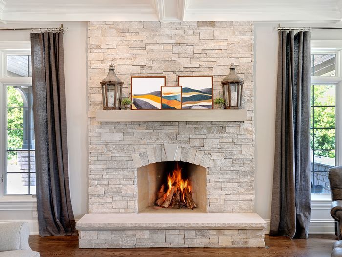 A stone fireplace with a mantel above it holding framed photos.