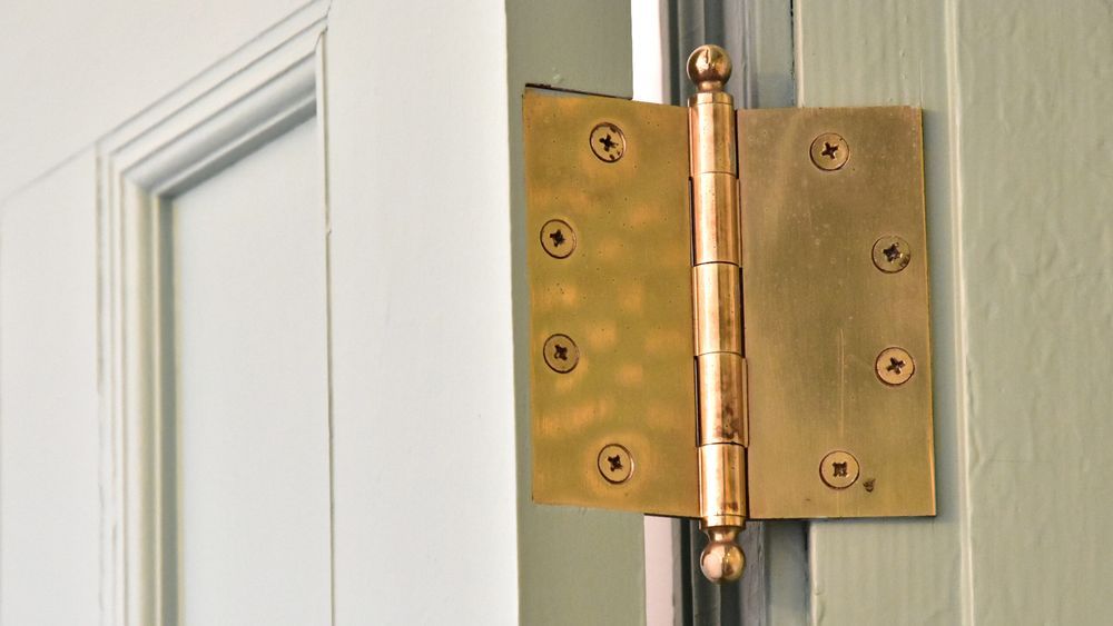 A loose door hinge on a white wooden door.