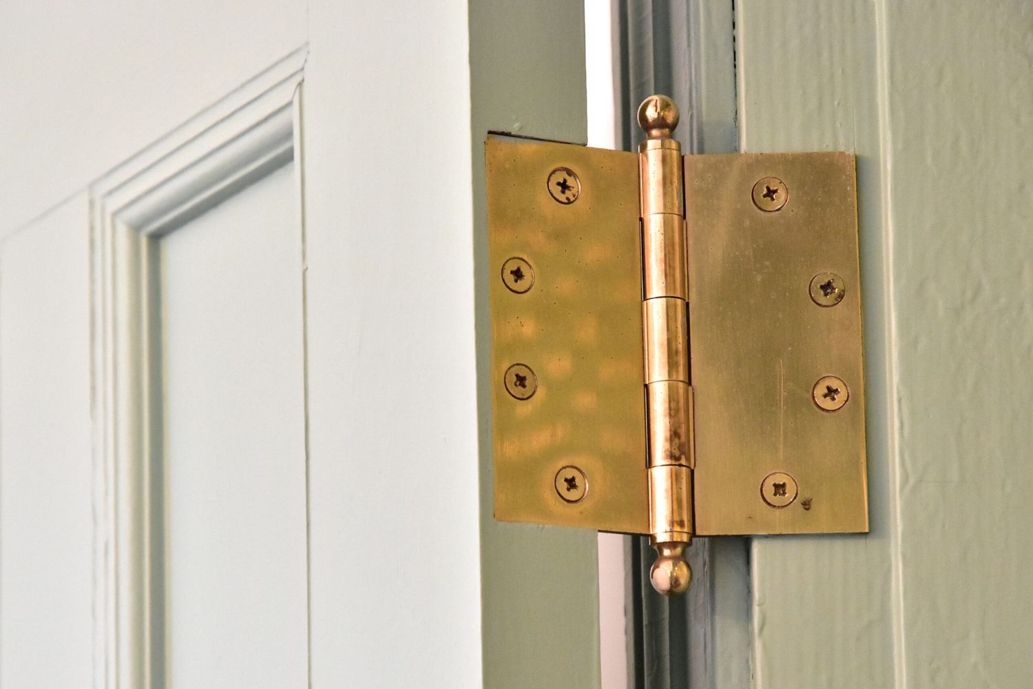 A loose door hinge on a white wooden door.