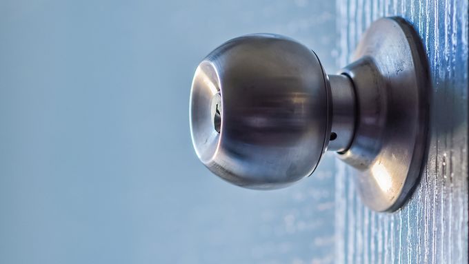 A silver interior doorknob on a blue wooden door.