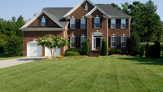 An organic lawn inf front of a brown brick home.