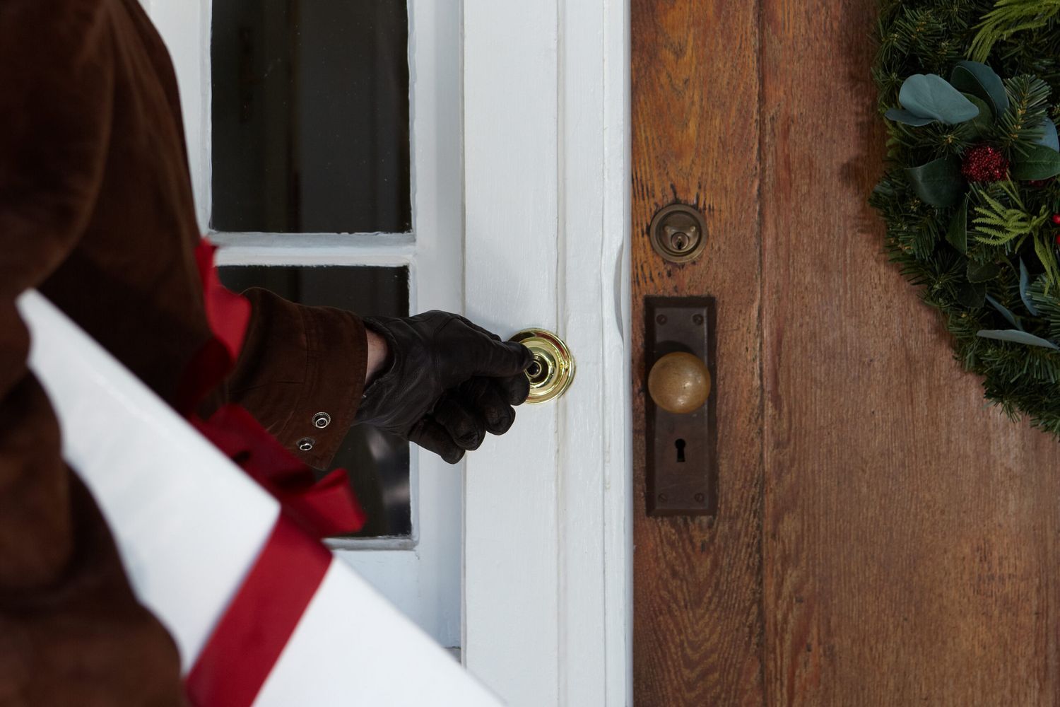 A man standing in front of a door, about to press a doorbell button.