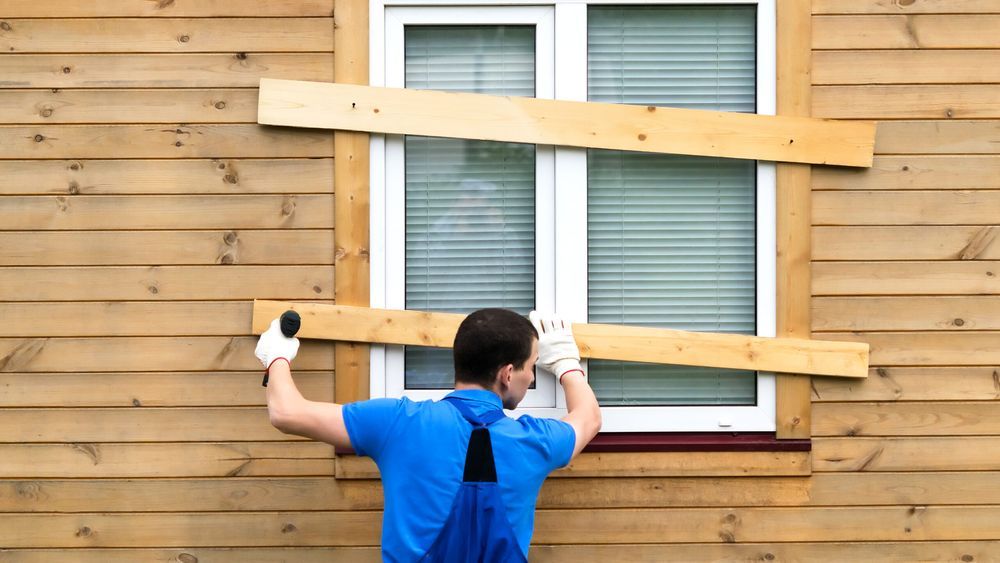 a man closes the windows with boards to protect the house during a long departure and hurricane