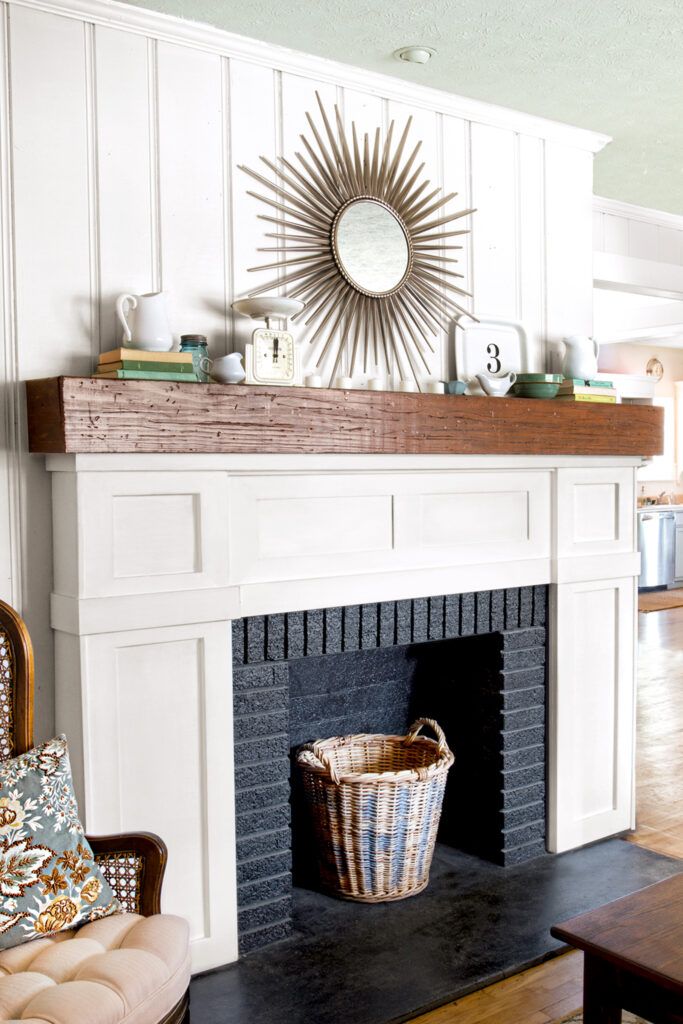 After: White wood trim brightens the fireplace, which is accented by a rustic mantelshelf; a black-painted firebox adds depth.