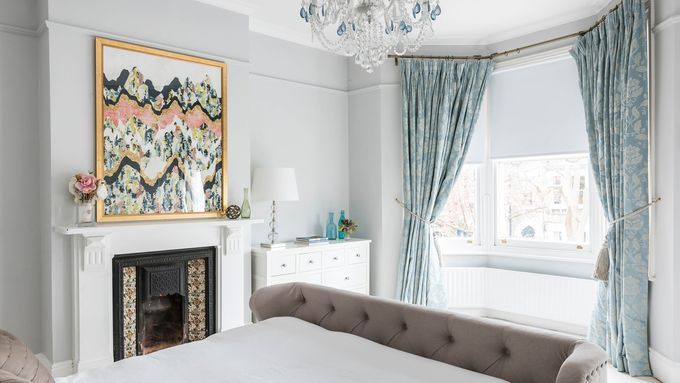 A bedroom with artwork hanging over the mantel.