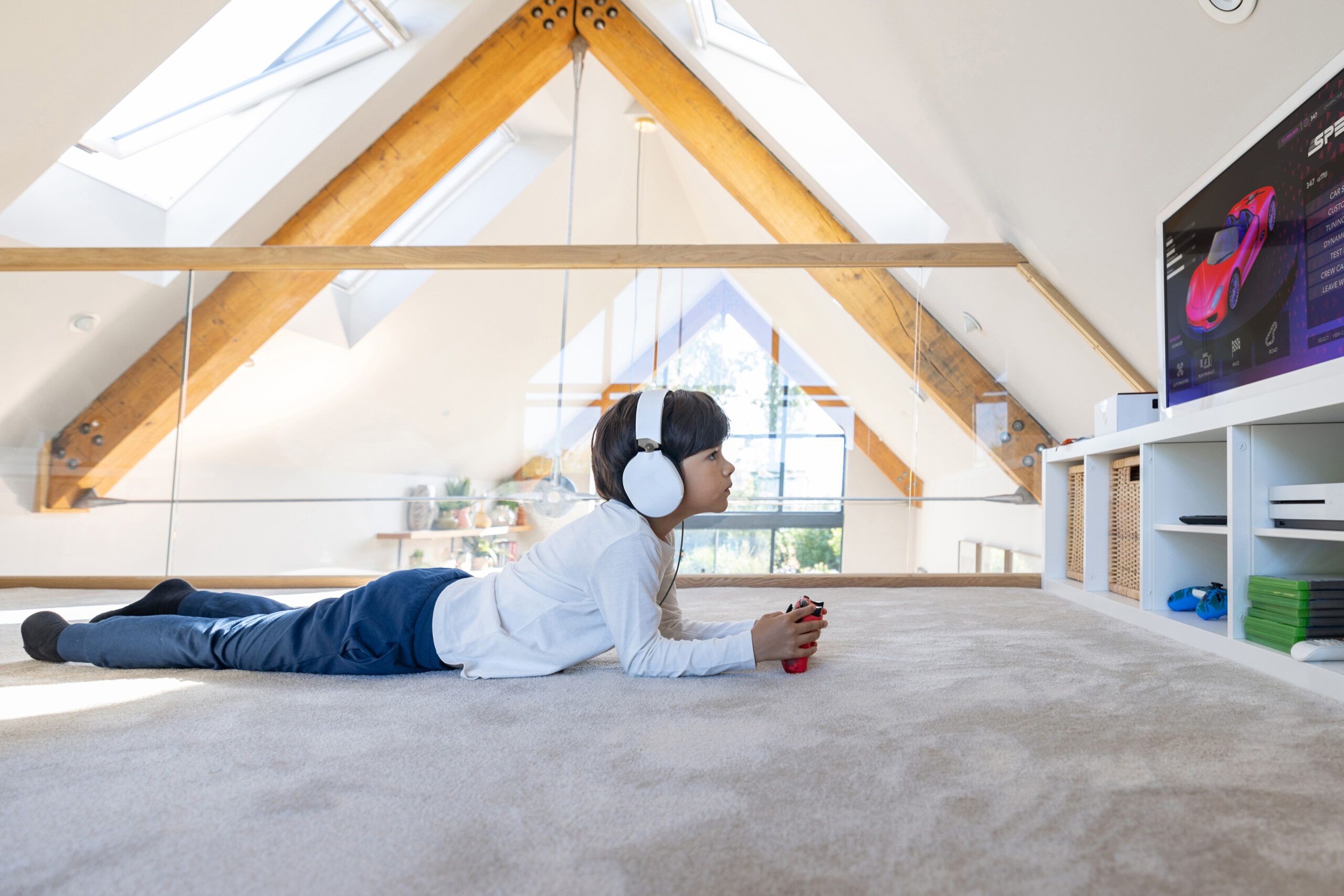 Boy playing video games while laying on a carpeted floor