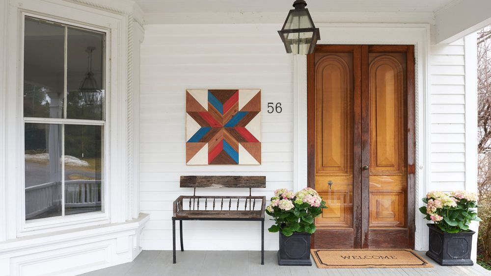 wooden quilt hanging on a porch wall next to an entryway