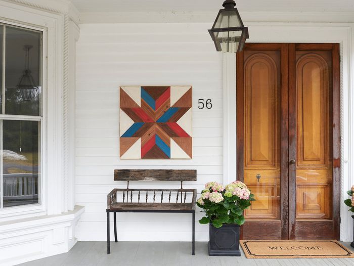 wooden quilt hanging on a porch wall next to an entryway