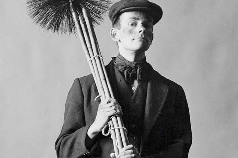 A black and white photo of a man holding a chimney cleaning tool.