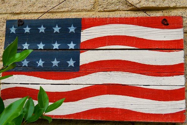 An image of an American flag painted on a wooden sign.