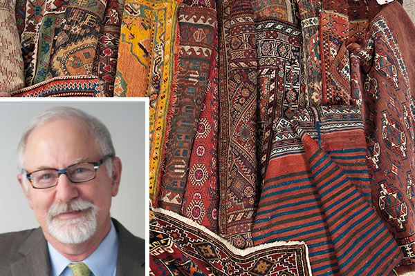 A headshot of auctioneer Stephen Fletcher with many different early American floor coverings.