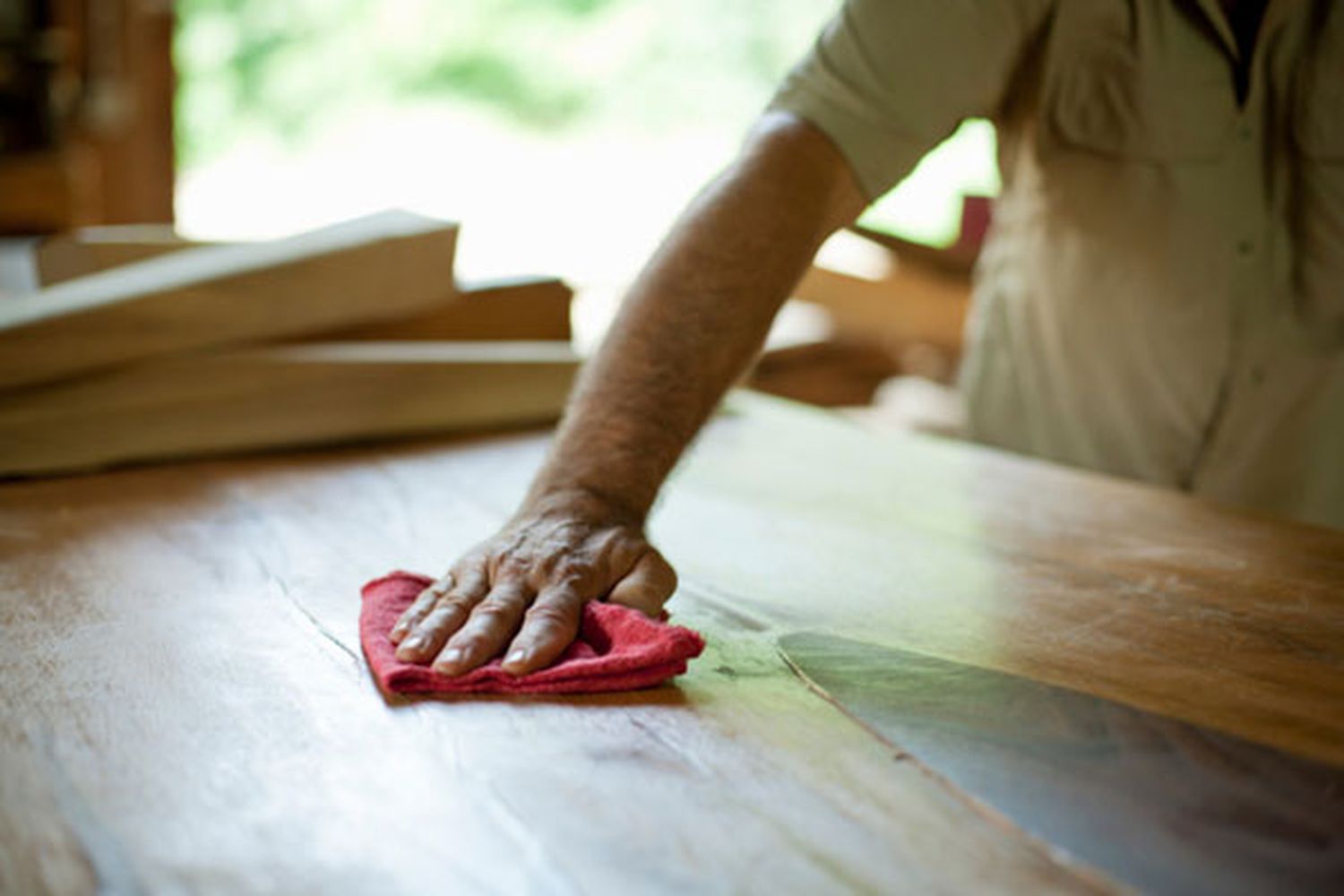 A man wiping a piece of wooden furniture with a cloth