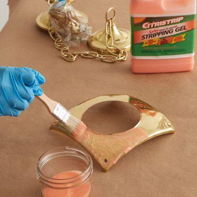 A person applying stripping gel to a brass fixture.