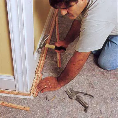 A man installs carpet tack strips.