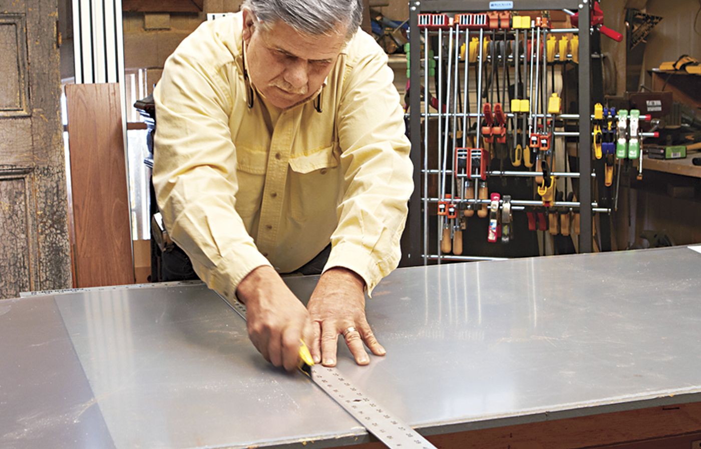 A man cutting the parts for a desk with a storage cubby.