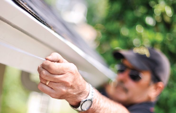 A man begins to calculate the pitch for his half-round gutter system.