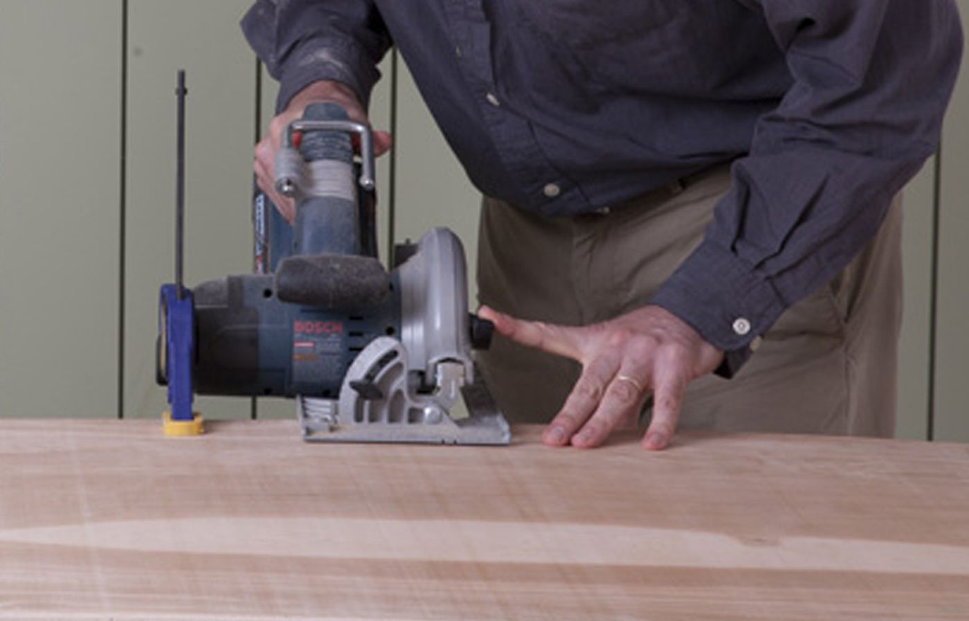 A man cuts the plywood base for a Halloween witch's cauldron.