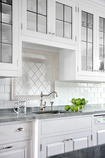 A kitchen sink on a marble countertop in front of a white tiled wall.