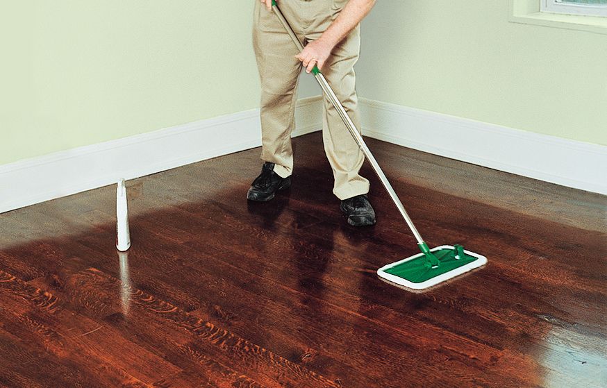 A person cleans the floors with hardwood cleaner and a microfiber flat mop.