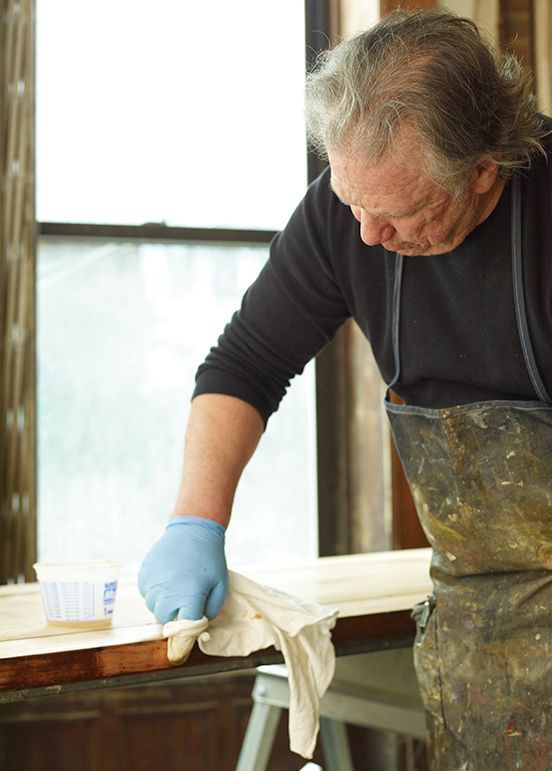 A man applies a wood finish to a wood beam.