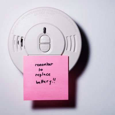 a smoke detector with a note on it to replace the battery