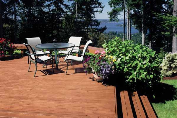 A stained wood deck with potted plants and a patio set.