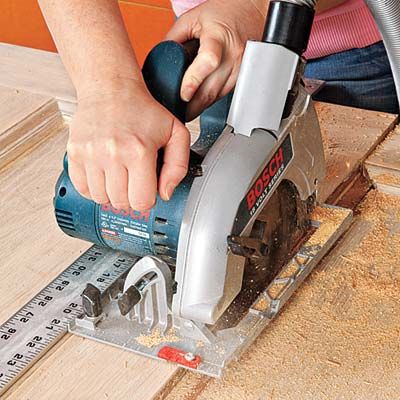 A person cuts a wooden door with a circular saw to turn it into a headboard.