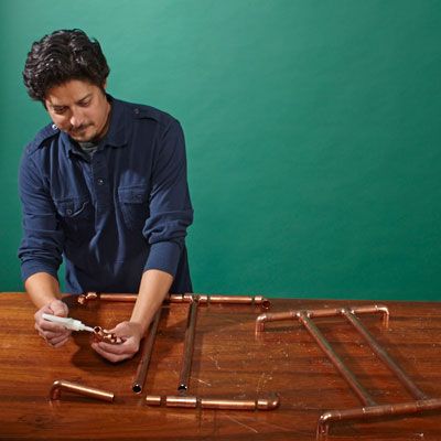 A man constructs copper pipe framing.