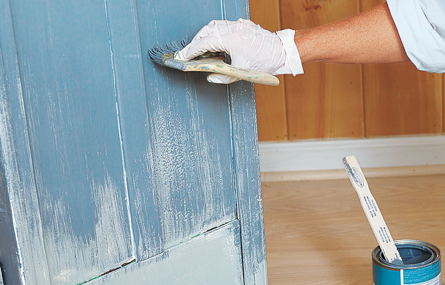 A person painting a piece of furniture in a faux aging style.