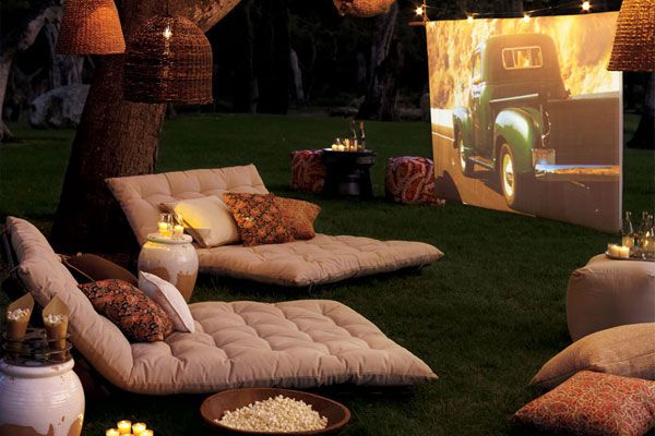 an outdoor movie night with pillows, popcorn, and a movie screen