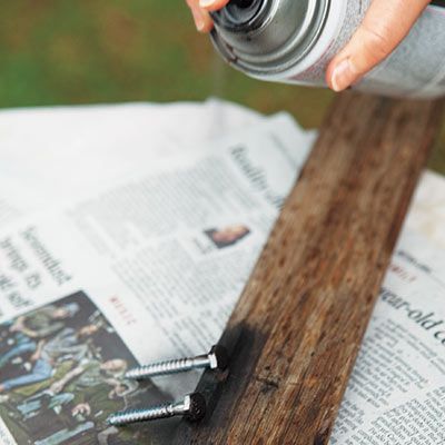 A person spray painting the fasteners for a pot rack.