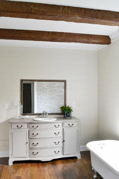 Faux wood beams in a period-style primary bathroom.