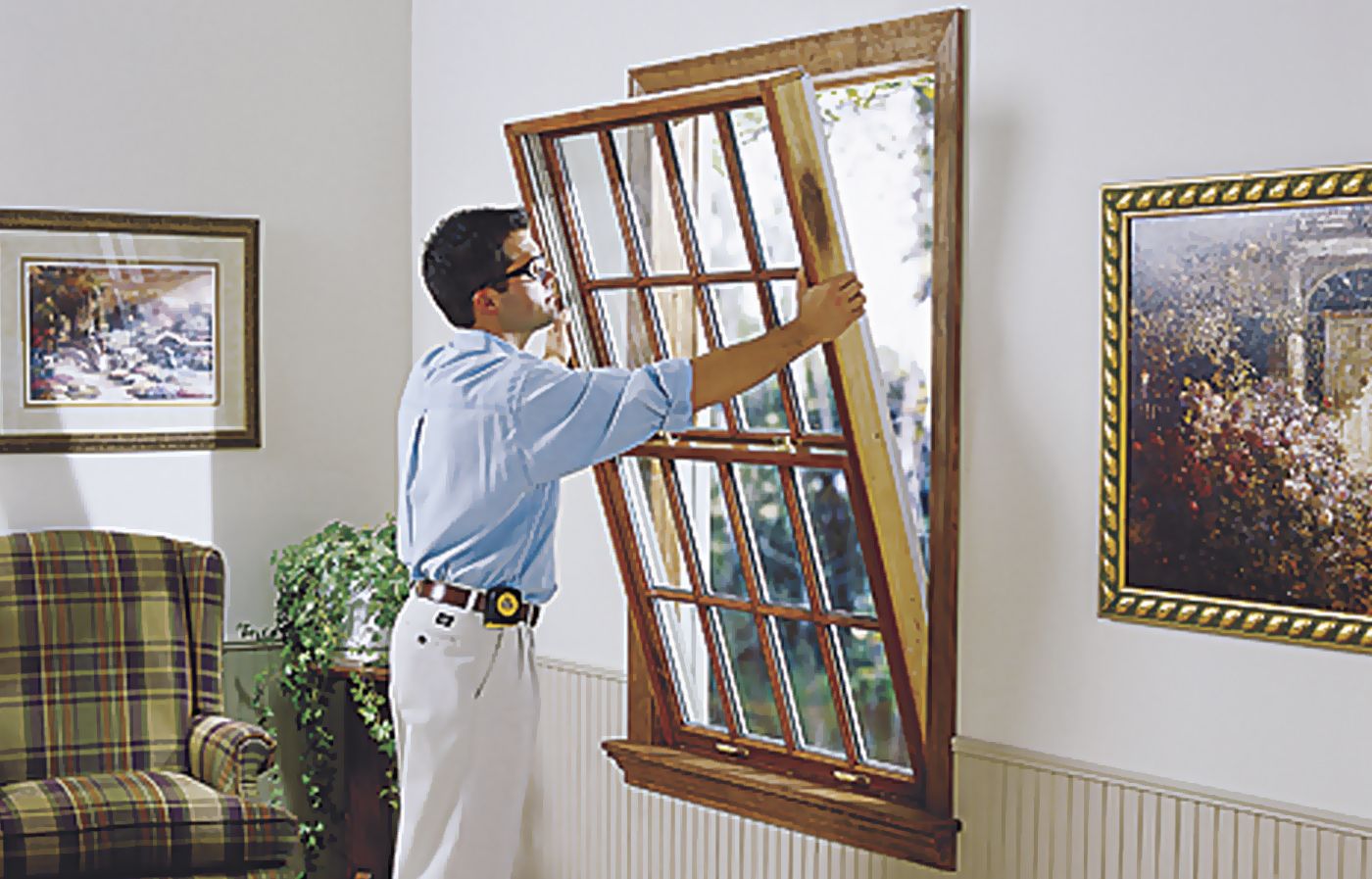 A man installs a wooden window in a house.