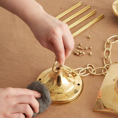 A person scrubbing a brass fixture with steel wool.