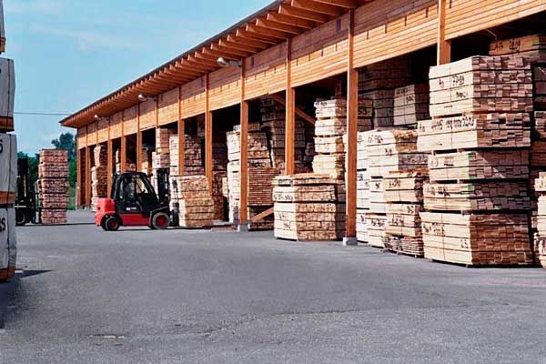 A forklift picking up pallets of hardwood decking material.