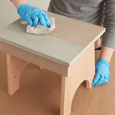 wiping off excess stain from a wood table and allowing it to dry