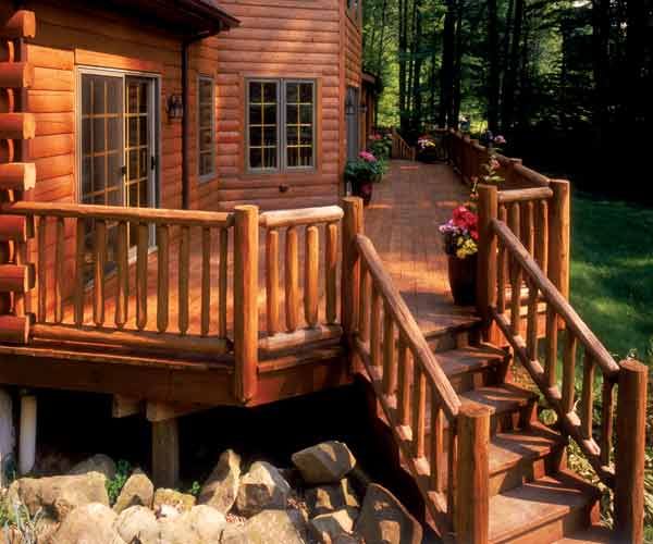 A large wood deck stained to match the color of the log cabin it's attached to.