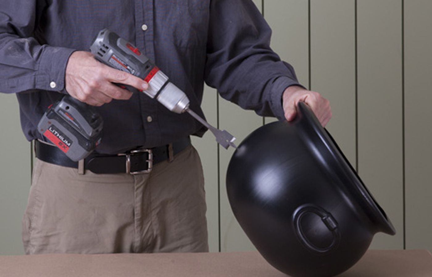 A man begins to craft the cauldron body of his Halloween witch's cauldron.