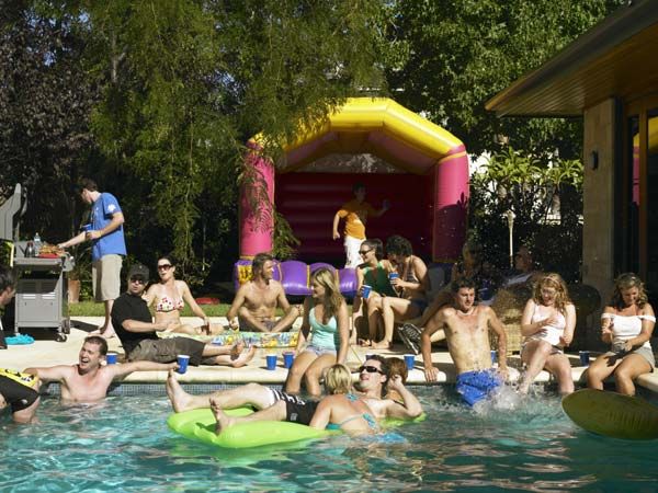 a big pool party in a backyard with a bouncy house