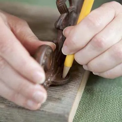 A person marks with a pencil where brackets will go to hold the towel rack shelf.
