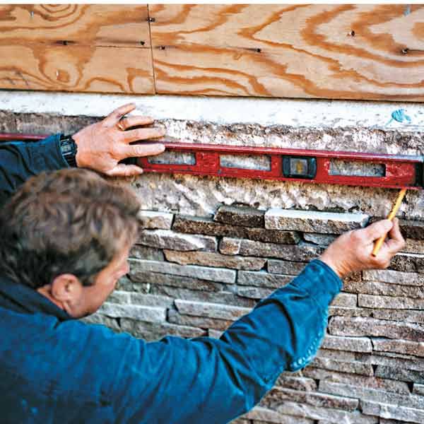 Contractor installing stone veneer siding to a home.