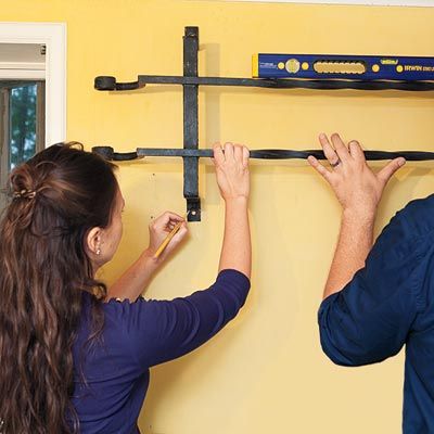 Two people using a level to find the ideal place for a pot rack.