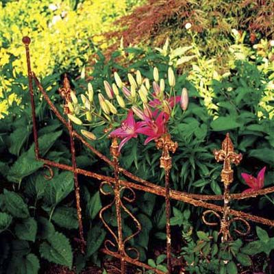 an old metal and rusted fence that is used to contain plants in a garden