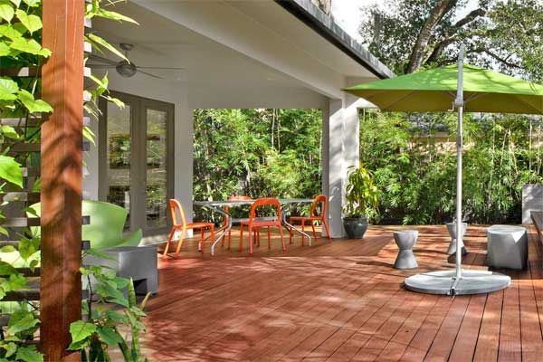 A deck with a hardwood floor, chairs, a table, and an umbrella.