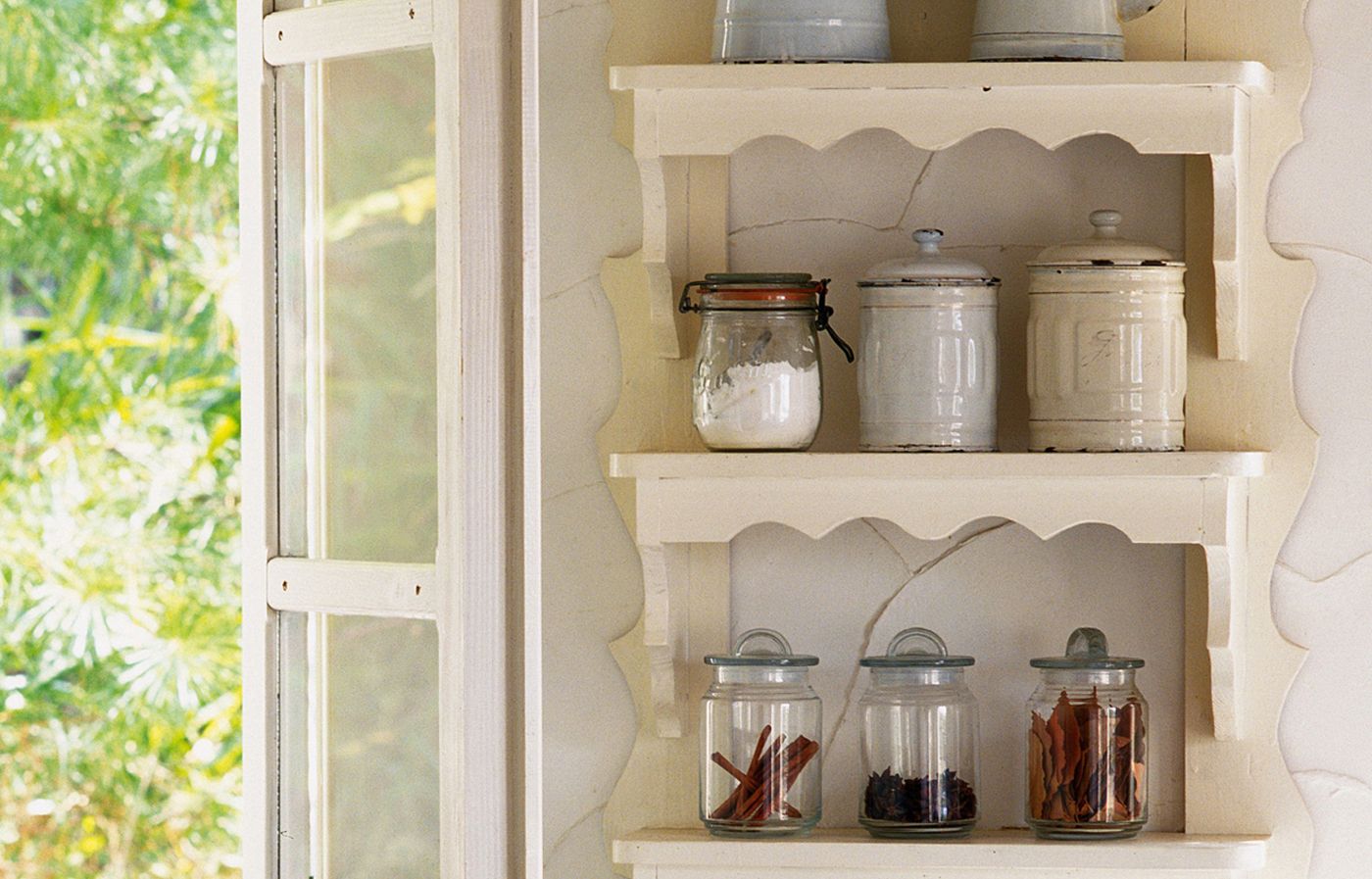 Open kitchen shelves with common kitchen ingredients on the bottom shelves.