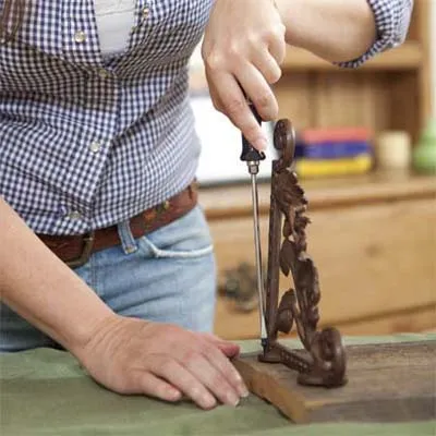 A woman screws the brackets on the back piece of the towel rack.