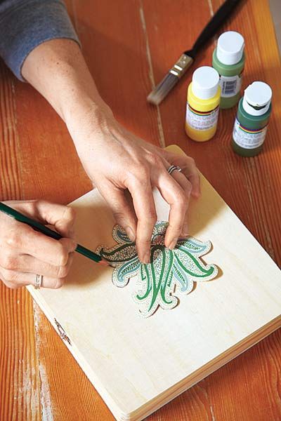 A person using a pencil to draw a pattern onto a wallpaper scrap.